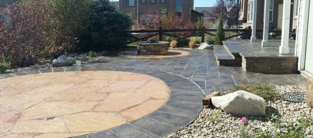 Image of a backyard outdoor living space in Colorado Springs featuring a round flagstone patio and fire pit