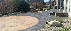 Image of a backyard outdoor living space in Colorado Springs featuring a round flagstone patio and fire pit