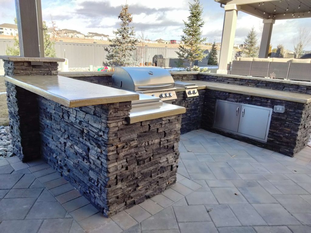 A backyard in Colorado Springs with custom landscape design featuring a professionally built patio, outdoor kitchen, and entertaining area.