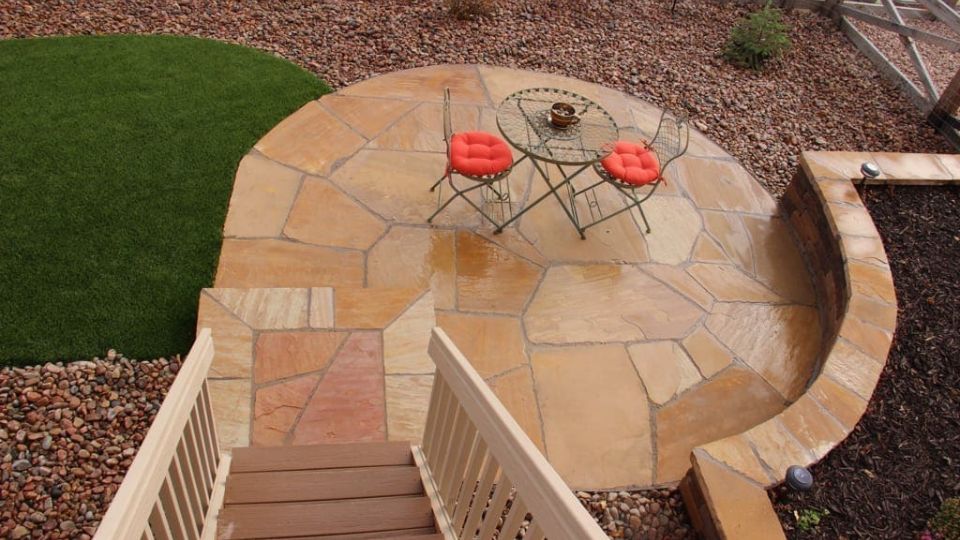 Image of a luxury outdoor living space in Colorado Springs featuring a round flagstone patio and fire pit