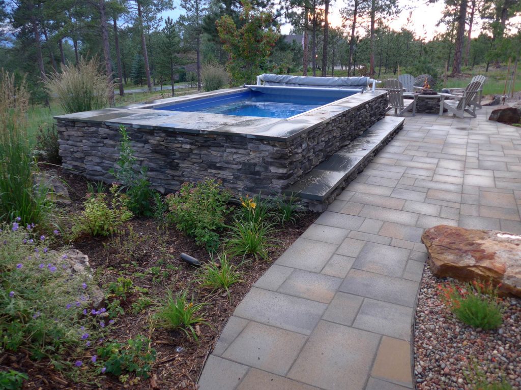 Image of swim spa and a custom backyard patio and landscape design project in Colorado Springs with natural stone surfaces