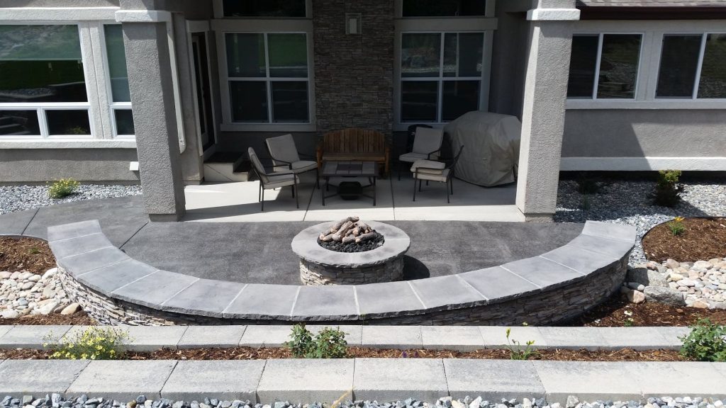 Backyard patio installation in Colorado Springs featuring natural stone surfaces, fire pit seating, and custom outdoor living design