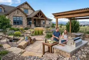 Image of luxury home with people enjoying outdoor living in Colorado Springs on their flagstone patio and outdoor kitchen.