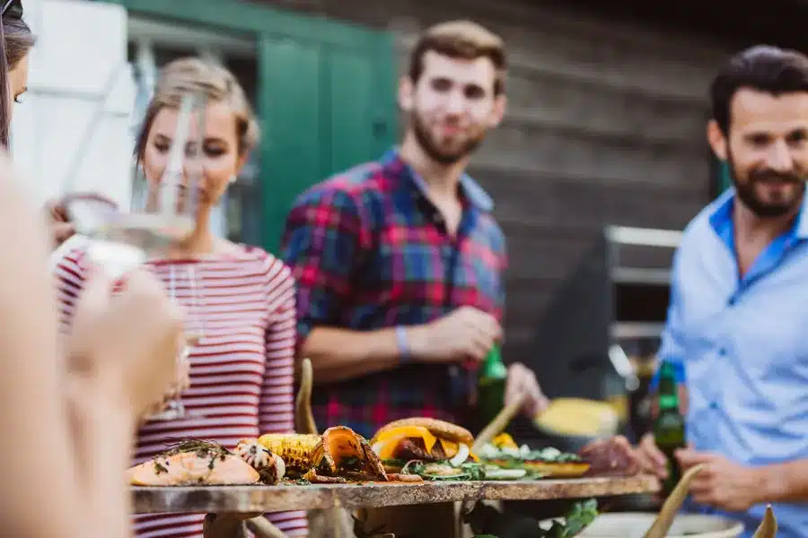 Young adults socializing outdoors in a backyard with outdoor kitchen.